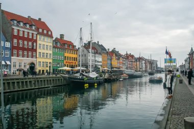 Kopenhag, Danimarka; 02: 14 2016. Nyhavn, Kopenhag kanallarının yanındaki ünlü cadde. Rıhtıma yanaşan teknelerin yanındaki binaların renkli cepheleri tuhaf bir manzara oluşturuyor..