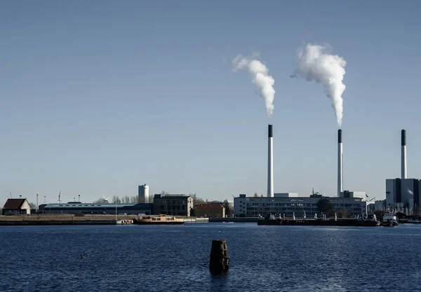 Copenhagen\'s industrial port with its smoking smokestacks on a sunny winter day. Industrial and commercial area of Copenhagen on the Baltic Sea. Denmark.