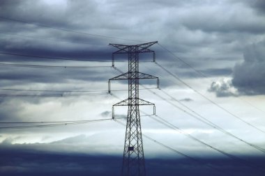 Elektrik iletimi için yüksek voltaj kuleleri. Resim bulutlu bir günde çekildi. Siluetin karanlık gökyüzüne karşı durduğu yerde..