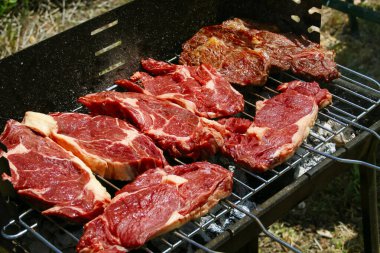 Lezzetli ızgara biftekler pişiriyorum. Mangalın güneş ışığında yakın görüntüsü.