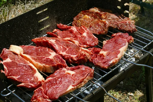 Lezzetli ızgara biftekler pişiriyorum. Mangalın güneş ışığında yakın görüntüsü.