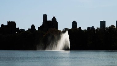 Jacqueline Kennedy Onassis Reservoir 'in New York, ABD' deki şehir manzarası. Central Park 'ın güneyindeki gökdelenlerin arka ışıklandırılmış silueti Jacqueline Kennedy Onassis Reservoir' da görüldüğü gibi..