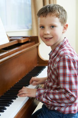 Portrait Of Young Boy Playing Piano At Home clipart