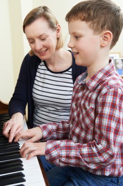 Boy With Music Teacher Having Lesson At Piano clipart