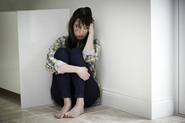 Female Victim Of Domestic Abuse Sitting On Floor