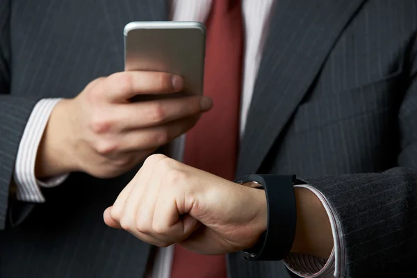 Hombre de negocios Sincronización de reloj inteligente con teléfono móvil —  Fotos de Stock