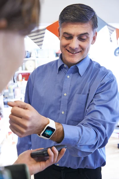 Hombre usando la aplicación de pago sin contacto en el reloj inteligente en la tienda —  Fotos de Stock