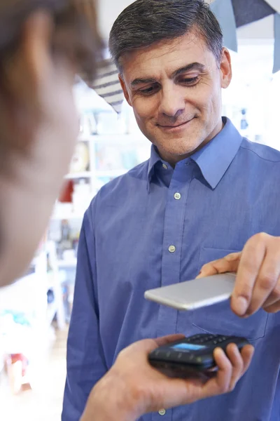 Hombre usando la aplicación de pago sin contacto en el teléfono móvil en la tienda —  Fotos de Stock