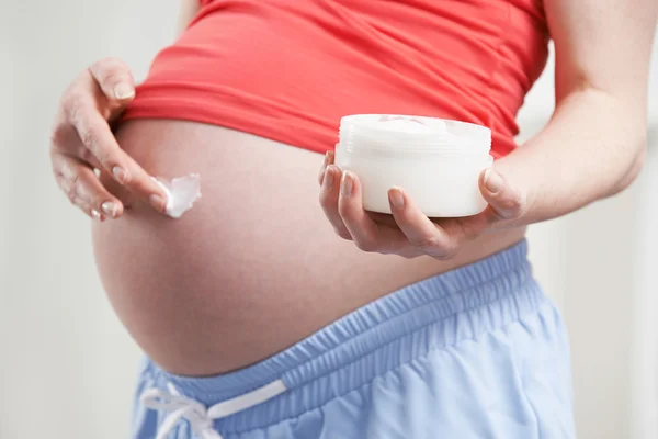 Gros plan de femme enceinte hydratant ventre — Photo