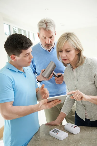 Sicherheitsberater demonstriert reiferem Paar Alarmanlage — Stockfoto