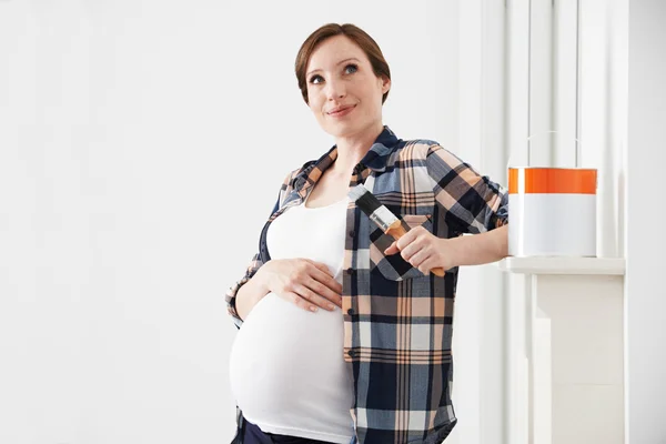 Беременная женщина делает перерыв, украшая детскую — стоковое фото
