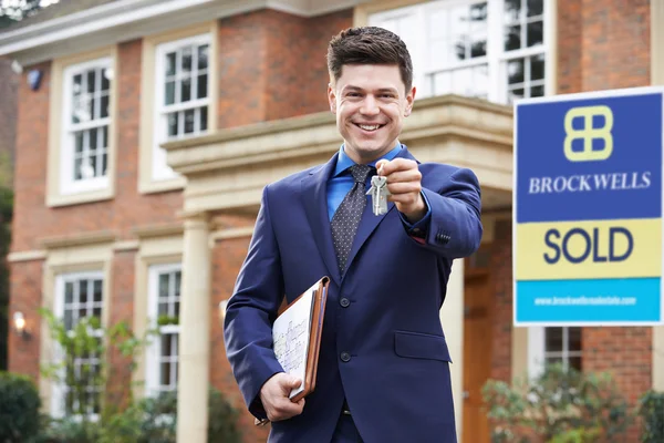 Mannelijke Realtor permanent buiten residentieel onroerend goed bedrijf sleutels — Stockfoto