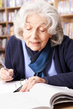 Kitaplığı'nda okuyan kadın kıdemli