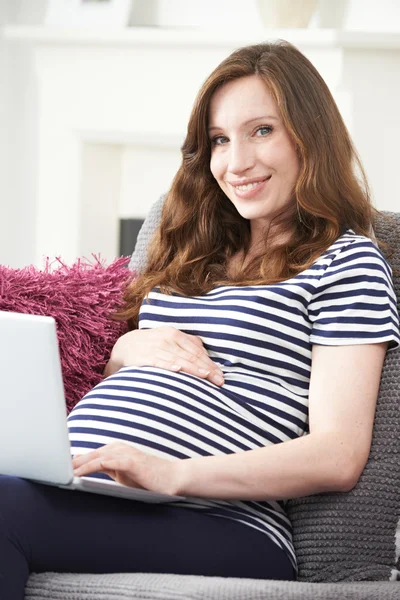 Femme enceinte utilisant un ordinateur portable à la maison — Photo