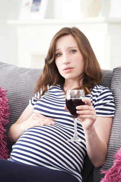 Besorgte Schwangere zu Hause trinkt Glas Rotwein — Stockfoto