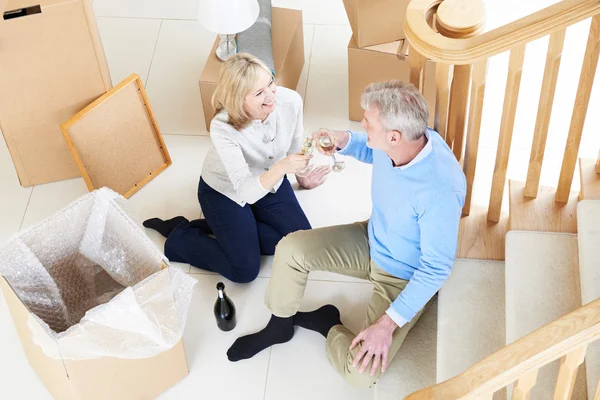 Pareja celebrando mudarse a un nuevo hogar con champán — Foto de Stock