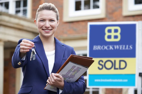 Immobilienmaklerin steht mit Schlüssel vor Wohnhaus — Stockfoto