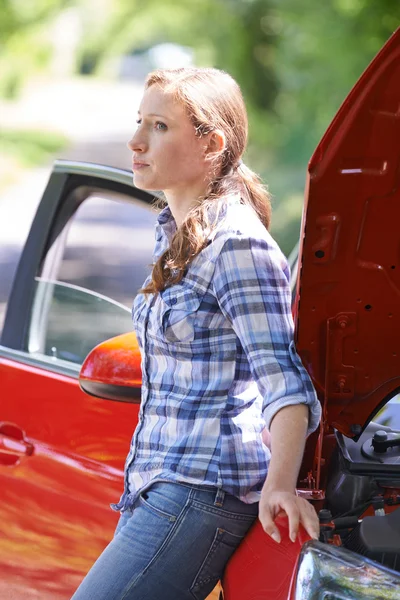 Preocupada motorista femenina de pie junto a un coche roto — Foto de Stock