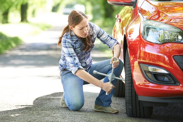Motorista fêmea frustrada com ferro de pneu tentando mudar a roda — Fotografia de Stock