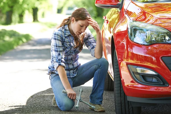 Conductor femenino frustrado con hierro de neumático tratando de cambiar la rueda — Foto de Stock