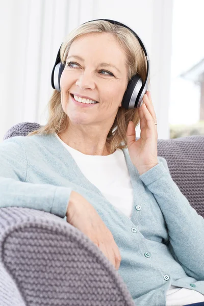 Mogen kvinna lyssna på musik på trådlösa hörlurar — Stockfoto