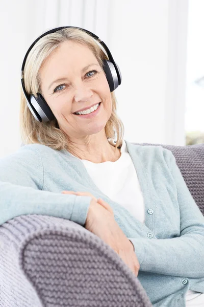 Mogen kvinna lyssna på musik på trådlösa hörlurar — Stockfoto