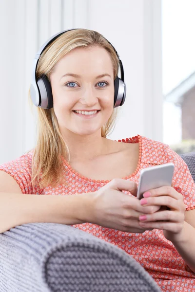 Mulher transmite música do telefone móvel para fones de ouvido sem fio — Fotografia de Stock