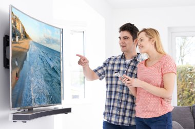 Genç çift evde yeni kavisli ekran televizyonlu