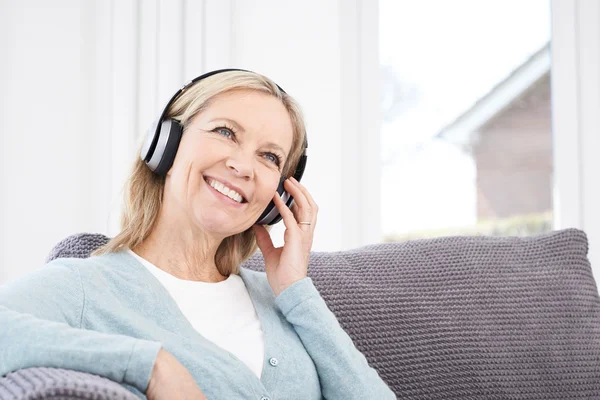 Mogen kvinna lyssna på musik på trådlösa hörlurar — Stockfoto