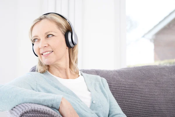 Mogen kvinna lyssna på musik på trådlösa hörlurar — Stockfoto