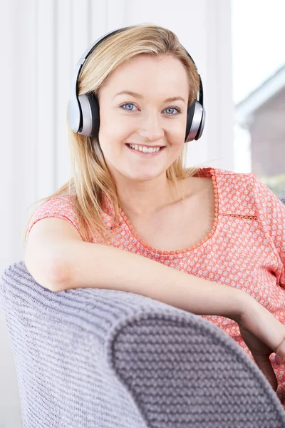 Mulher jovem ouvindo música em fones de ouvido sem fio — Fotografia de Stock