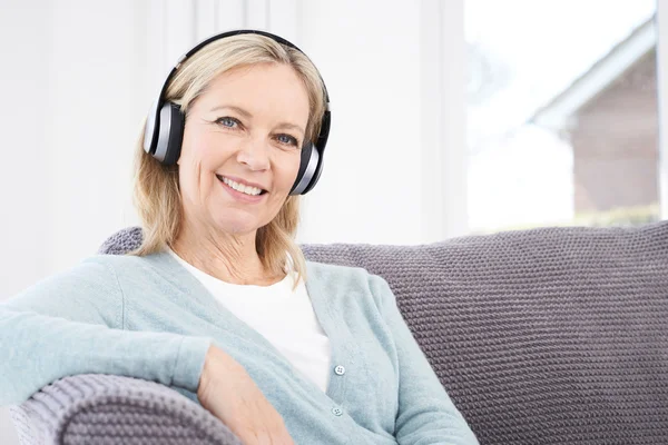 Mujer madura escuchando música en auriculares inalámbricos —  Fotos de Stock