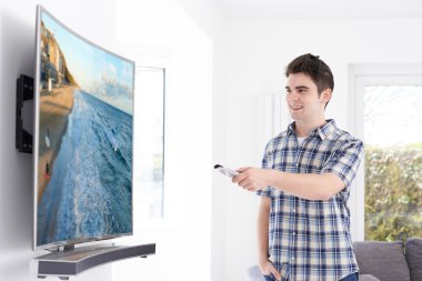Genç adam evde yeni kavisli ekran televizyonlu