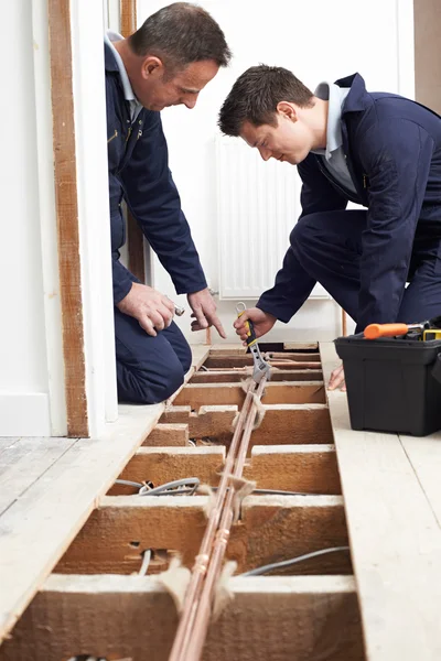 Rörmokare och lärling montering centralvärme i huset — Stockfoto