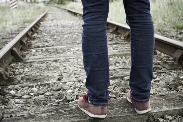 Крупный план ступней человека, стоящих между железнодорожными путями — стоковое фото
