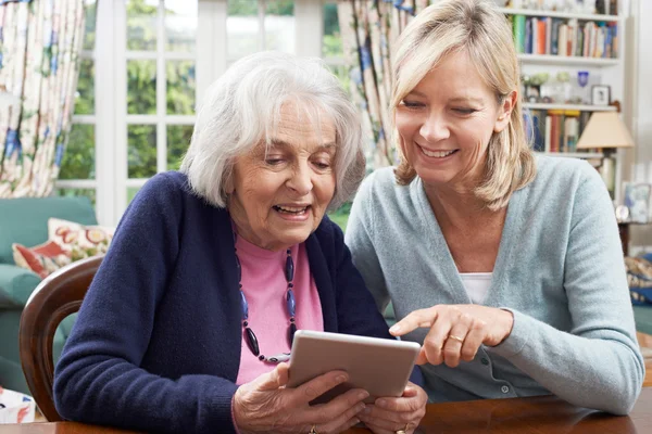 Соседка показывает пожилой женщине, как пользоваться цифровым планшетом — стоковое фото
