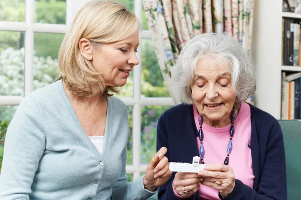 Nachbarin hilft Seniorin mit Medikamenten — Stockfoto