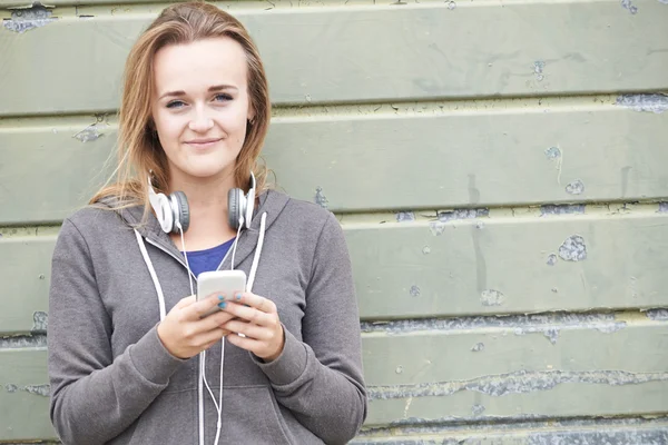 Tonårsflicka bär hörlurar och lyssna på musik i urban — Stockfoto