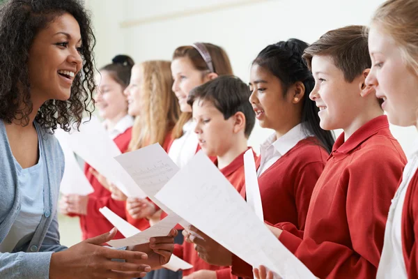 Niños en el coro escolar siendo alentados por el maestro — Foto de Stock