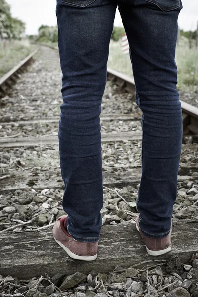 Primo piano dei piedi dell'uomo in piedi tra binari ferroviari — Foto Stock