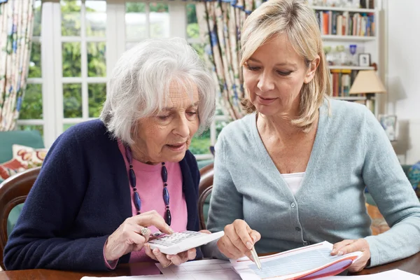 Zralé ženy pomáhají starší soused s domácí finance — Stock fotografie