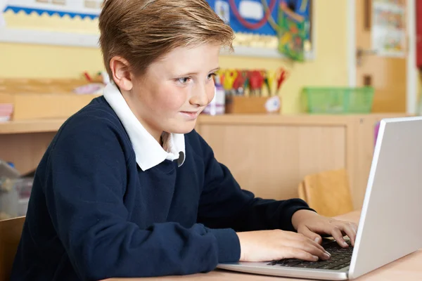 Alumno de la escuela primaria masculina usando el ordenador portátil en la clase de computadora — Foto de Stock