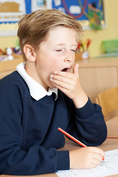 Aluno da escola primária masculina bocejando na sala de aula — Fotografia de Stock