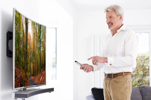 Érett férfi új hajlított képernyős televízió otthon — Stock Fotó