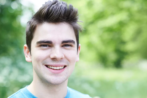 Utomhus huvud och axlar porträtt av leende ung Man — Stockfoto