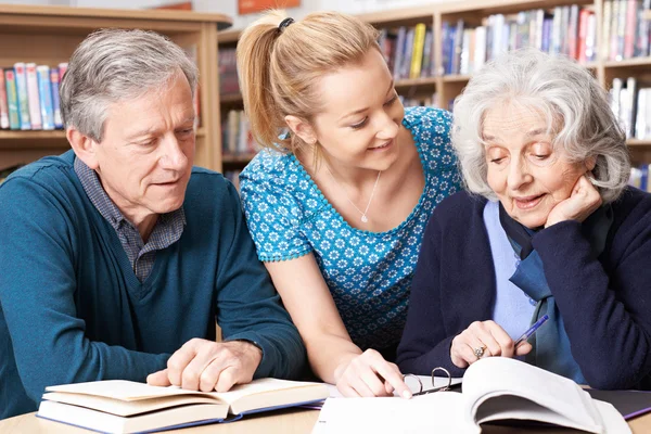Ältere Schüler arbeiten mit Lehrer in Bibliothek — Stockfoto