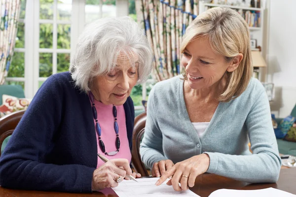 Mujer vecina ayudando a la mujer mayor a completar el formulario —  Fotos de Stock