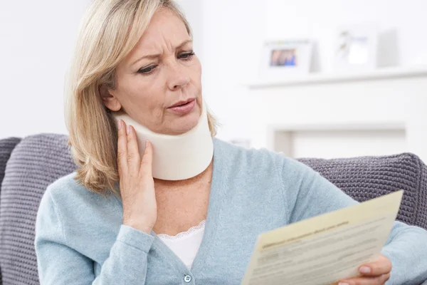 Reife Frau liest Brief nach Nackenverletzung — Stockfoto