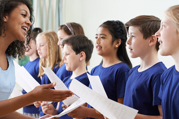 Group Of School Children With Teacher Singing In Choir 