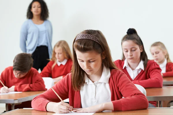 Aluno feminino na mesa fazendo exame escolar — Fotografia de Stock